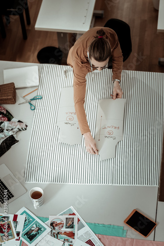 Tall fair-haired designer in a brown garment working with patterns photo