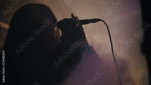 A woman vocalist emotionally sings on a smoky stage holding a mic