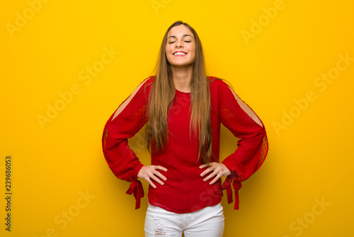 Young girl with red dress over yellow wall happy and smiling © luismolinero