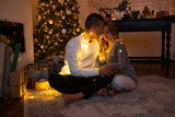 Couple in love sitting next to a Christmas tree. Magic light