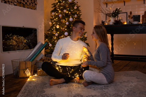 Wallpaper Mural Couple in love at home on Christmas tree on background. Magic light Torontodigital.ca