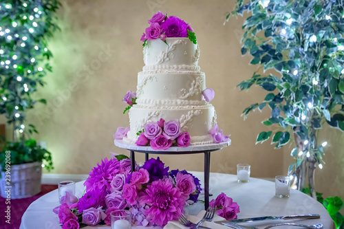 Three Tiered Wedding Cake with Purple Flowers on Table