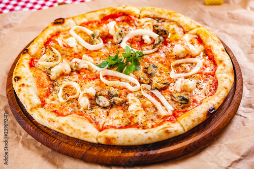 Italian Pizza with seafood and mozzarella cheese on wooden cutting board. Close up