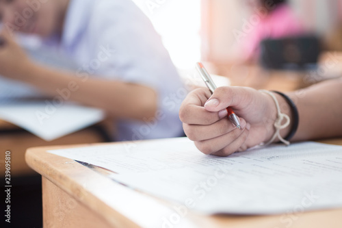 Close-up hand of students writing an exam in classroom with stress