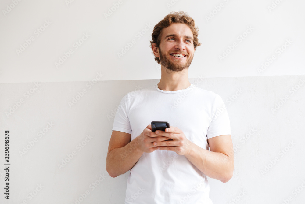Smiling young man holding mobile phone Smiling young man holding mobile phone