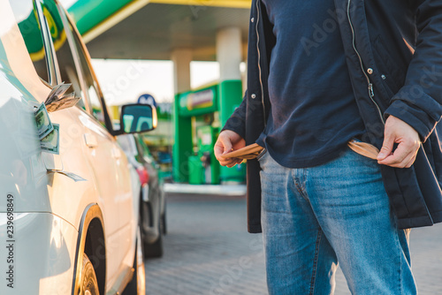 man shows empty pocket at gas station. money in car tank