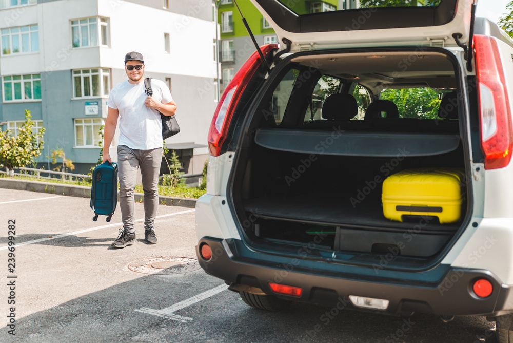man putting bags in car trunk. ready for car travel man putting bags in car trunk. ready for car travel