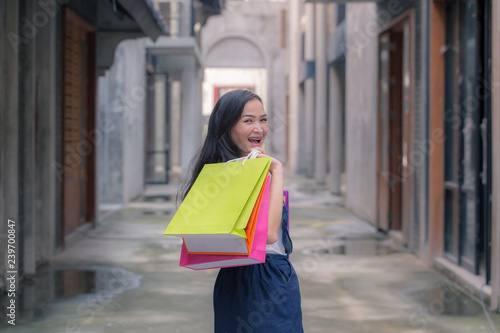 Beautiful asian woman hold colourful shopping bags on the super store street. Portrait shopaholic glamorous pretty beautiful  concept. Cheerful lady with happiness shopping center enjoy new fashion.