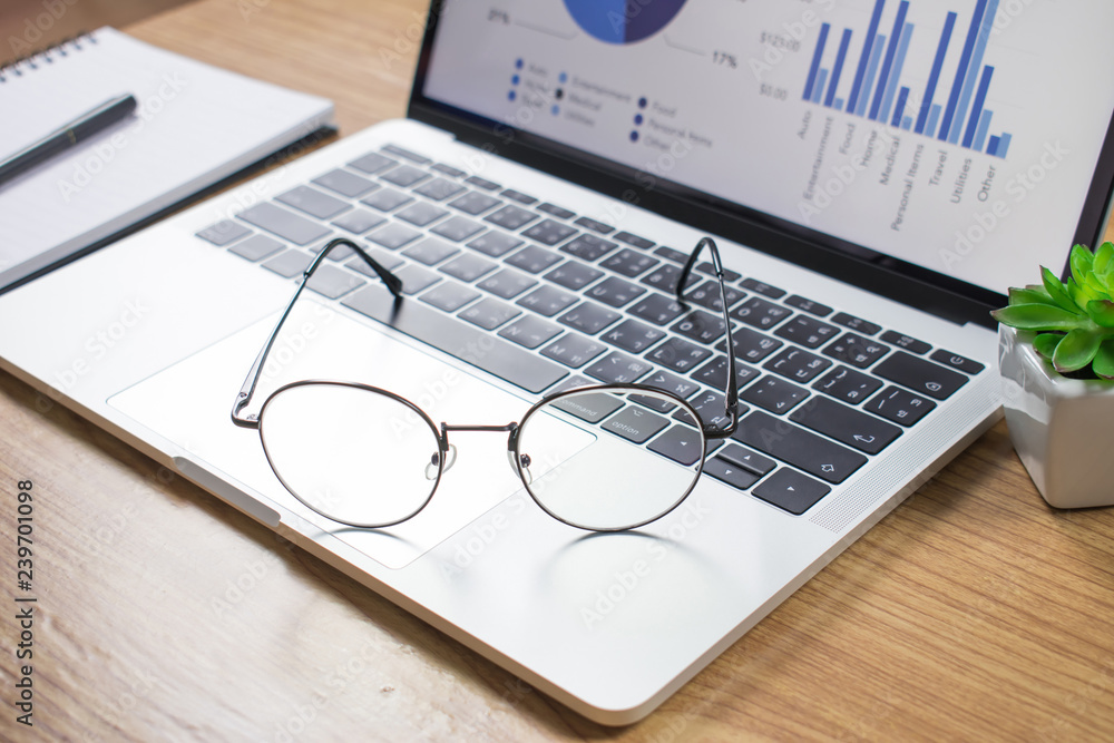 Photos of the desk with a laptop and glasses on a wooden table. Photos of the desk with a laptop and glasses on a wooden table.