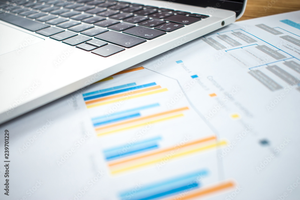 Financial charts and computers are on the wood table in the business concept. Financial charts and computers are on the wood table in the business concept.
