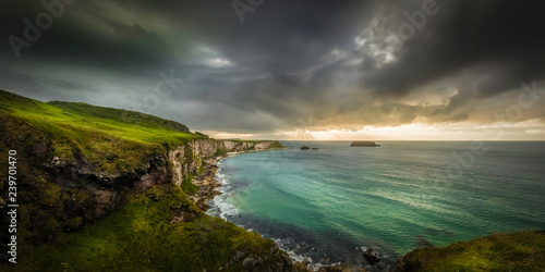 Scenic view with a dark clouded sky above the steep coastline of Ballintoy/Carrick-a-Rede in Ireland, and seen from the side of the famous Rope Bridge