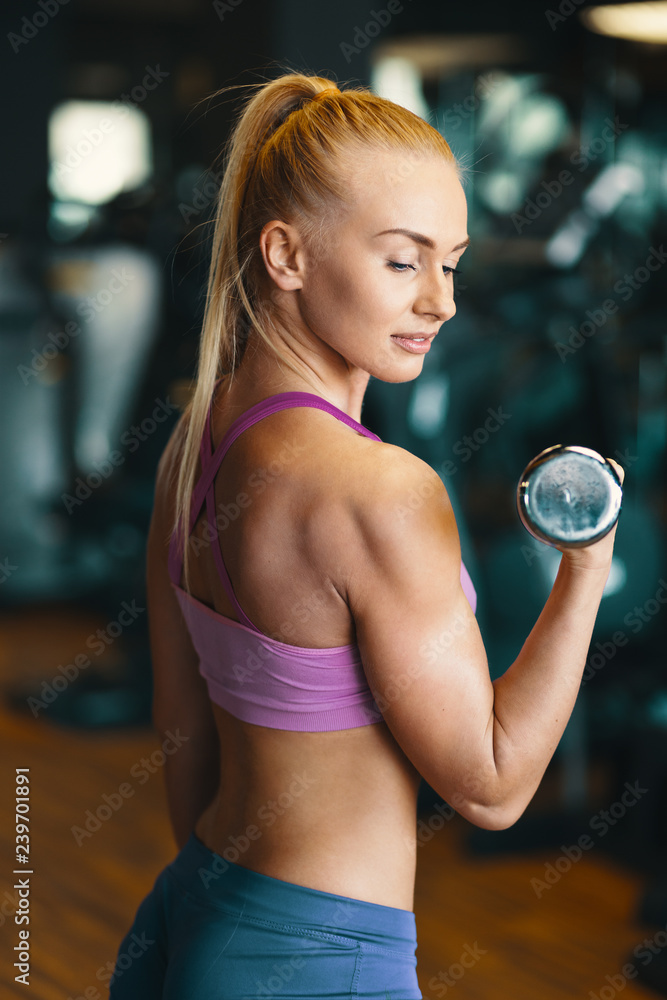 Young woman in pink top and mini shorts doing exercise with dumb Young woman in pink top and mini shorts doing exercise with dumb