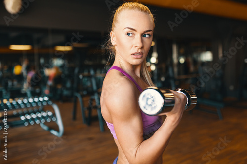 Young woman in pink top  doing exercise with dumbbells while tra photo