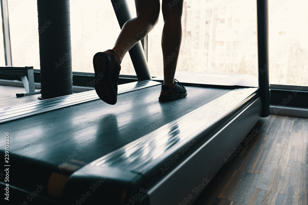 Early morning sport, female legs running on the gym treadmill ea Early morning sport, female legs running on the gym treadmill ea