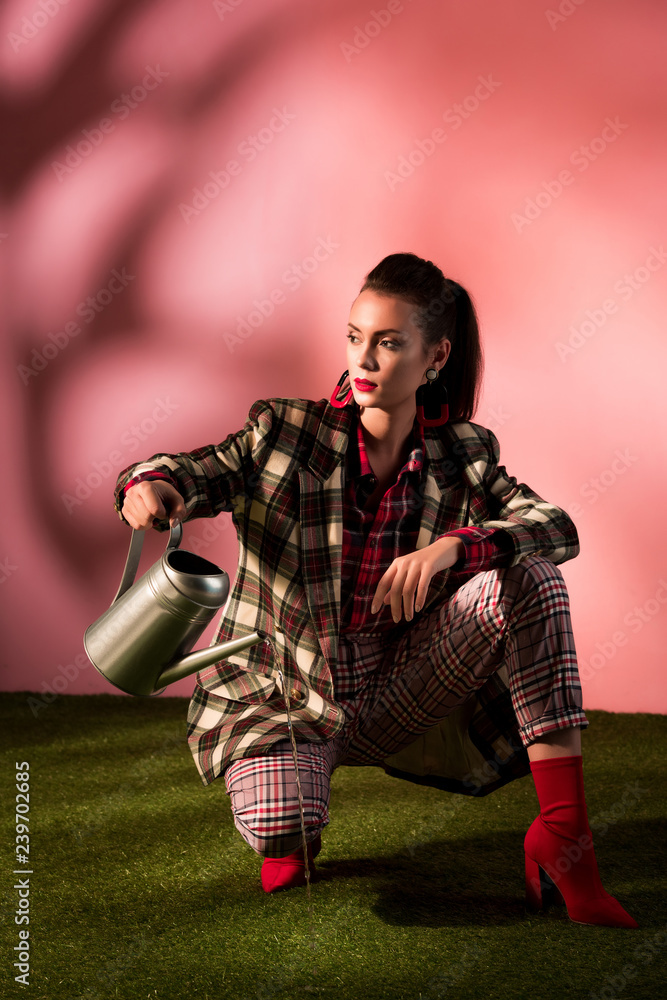 beautiful woman in fashionable checkered suit posing with watering can