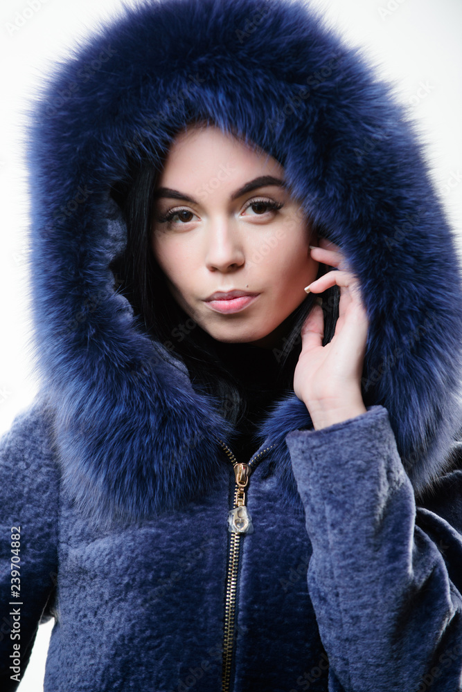 Girl posing hooded fur coat. Female with makeup wear dark blue soft fur coat.  Woman wear