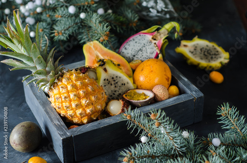Fototapeta Naklejka Na Ścianę i Meble -  Exotic, tropical fruits in a wood box- grenadilla, rambutan, passion fruit, kumquat, pineapple, papaya, pitahaya, lychee. Christmas present - fruit box.