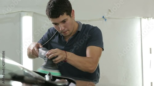 Mechanic polishing car in auto repair shop. photo