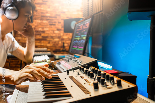 asian male composer playing midi keyboard synthesizer for making music in sound studio photo
