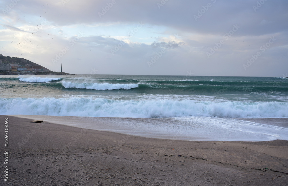 Waves breaking against Riazor Beach with sunset light. Wild sea with foam. La Coruna, Spain, autumn storm.