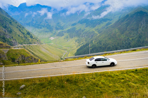 white car on a mountain road against backdroop of a beatifull landscape and blue sky © Romo Lomo