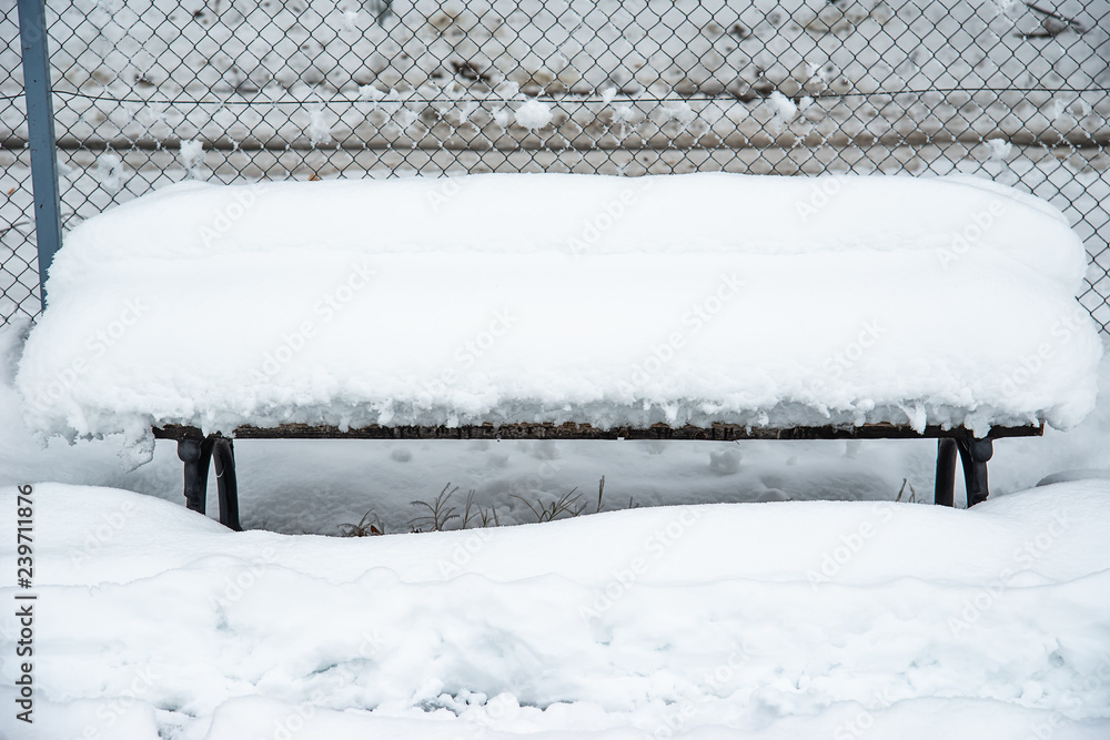 Wooden bench covered with snow in a park waits for companionship. Wooden bench covered with snow in a park waits for companionship.