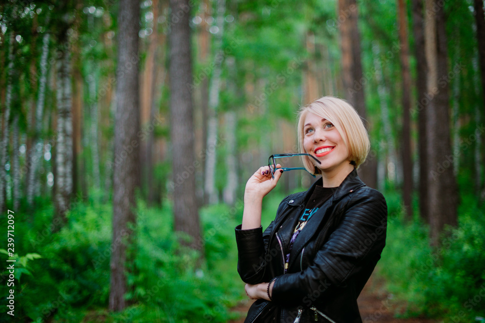 blonde girl holding glasses with a smile on her face in the forest blonde girl holding glasses with a smile on her face in the forest