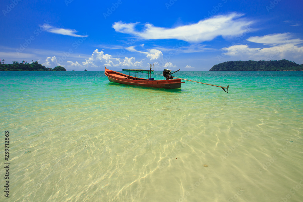 A fishing boat floating on beach with clean and clear sea and cloudy blue sky. Copy space. A fishing boat floating on beach with clean and clear sea and cloudy blue sky. Copy space.