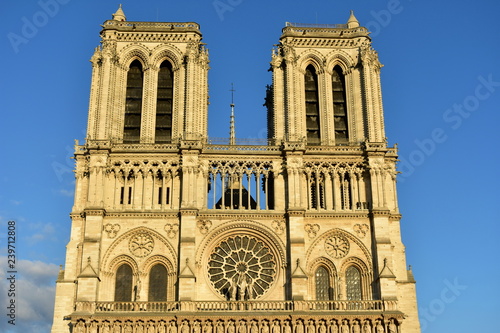 Notre Dame Cathedral, Paris, France. Towers, viewpoint, windows and spire with sunset light. Sunny day, blue sky.