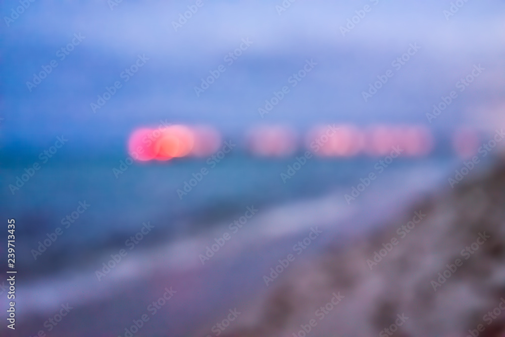 Sunny Isles Beach evening in Miami, Florida with sand, pier, waves crashing on shore coastline, colorful turquoise water, bokeh abstract background circles, illuminated red blurry blurred Sunny Isles Beach evening in Miami, Florida with sand, pier, waves crashing on shore coastline, colorful turquoise water, bokeh abstract background circles, illuminated red blurry blurred