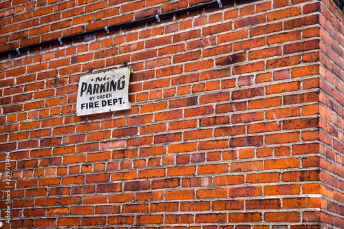 No parking sign on brick wall in summer