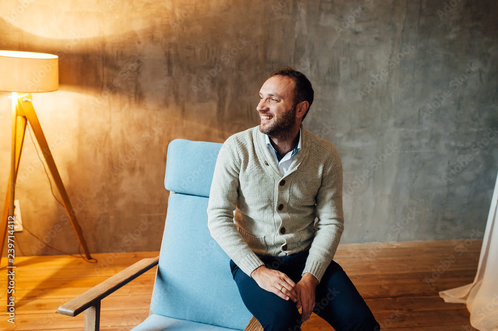 Positive happy man smiling in room with lamp Positive happy man smiling in room with lamp