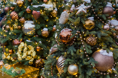 Christmas tree closeup. Golden balls and illuminated garland with flashlights.