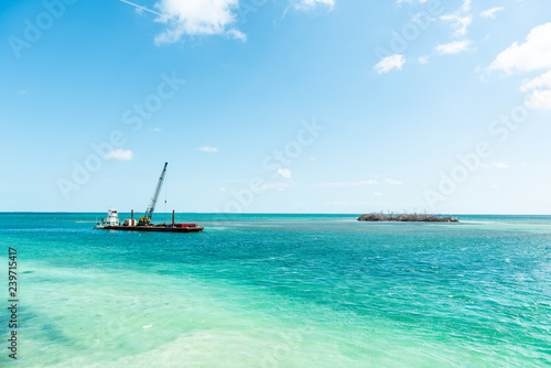 Marathon, USA Florida construction site crane building on island with colorful vibrant turquoise sunny water on gulf of mexico, industrial landscape