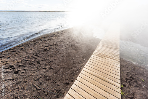 Laugarvatn lake in south Iceland on Golden Circle, shore water closeup Hot Springs Geothermal area, sunny day, steam vapor hot mist and wood boardwalk photo