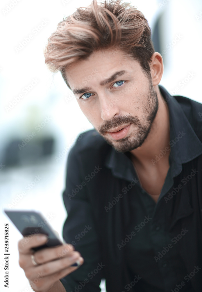 A stylish bearded male sits and uses a smartphone. A stylish bearded male sits and uses a smartphone.