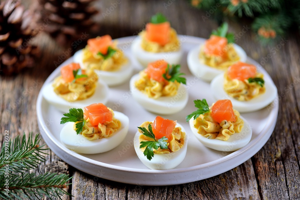 Stuffed chicken eggs with soft cheese, capers and salted salmon. Christmas background.