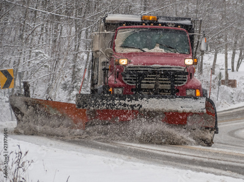 Snowplow clearing road during storm.