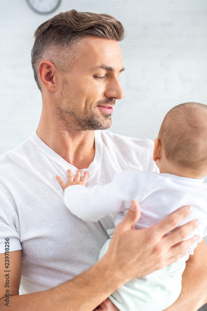 Fototapeta premium handsome father holding baby at home