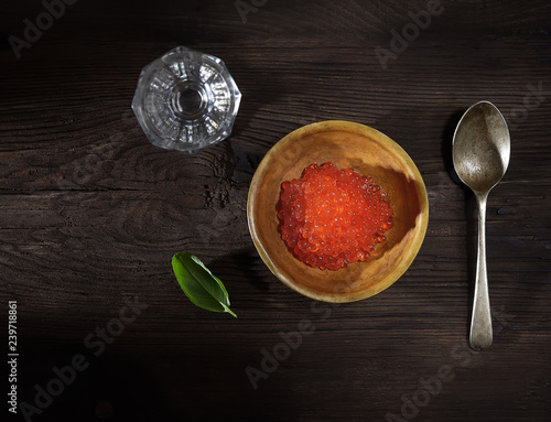 red caviar and a glass of vodka on a wooden background. top view. rustic style.