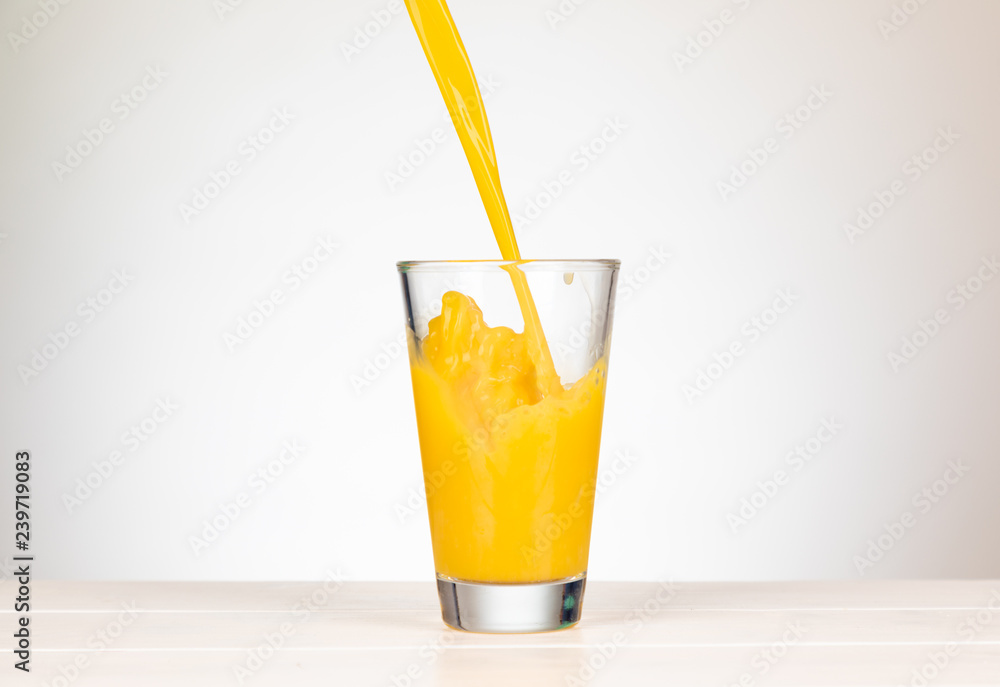 pour orange juice in a glass with splashing pour orange juice in a glass with splashing