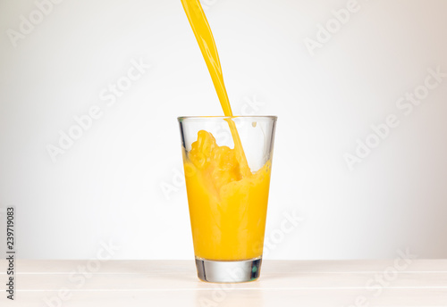pour orange juice in a glass with splashing