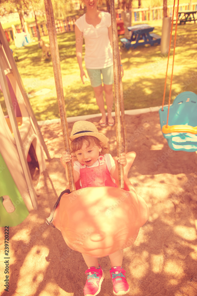 mother and daughter swinging in the park mother and daughter swinging in the park