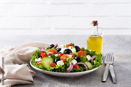 Fresh Greek salad in Plate with black olive,tomato,feta cheese, cucumber and onion on gray background