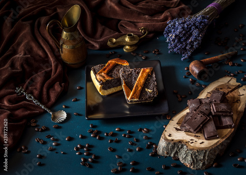 Arrangement of slice chocolate cake and pieces of coffee and chocolate on dark background. Homemade chocolate cake served with pieces of chocolate. Holiday arrangement