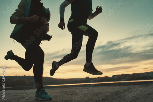 Sportive people legs running at sunrise