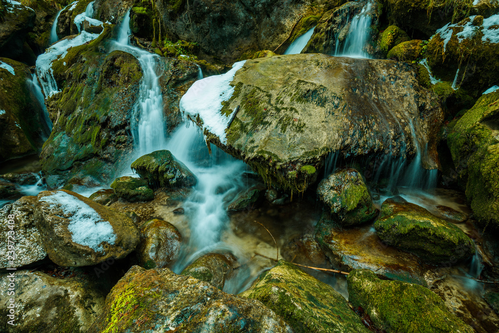 beautiful waterfall in lower Austria shot on a cold winter afternoon with a bit of ice on the sides and green moss growing on logs and rocks beautiful waterfall in lower Austria shot on a cold winter afternoon with a bit of ice on the sides and green moss growing on logs and rocks