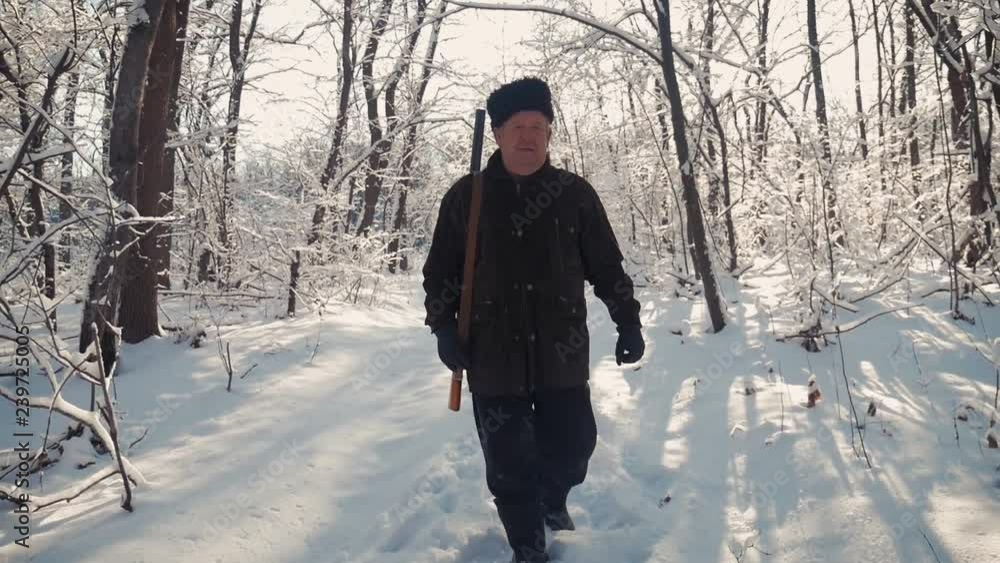 Hunter walking in the snowy winter forest. Winter hobby, sun, hunting concept. Hunter walking in the snowy winter forest. Winter hobby, sun, hunting concept.