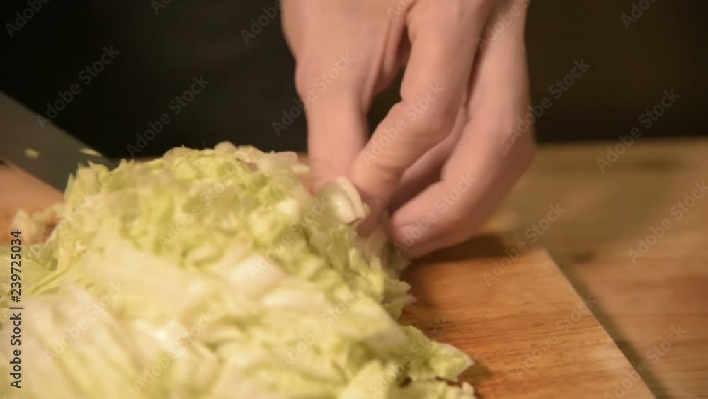 Close-up of hands of a girl at the home kitchen on a wooden cutting board knives Pikinsky cabbage for salad. Home cooking Close-up of hands of a girl at the home kitchen on a wooden cutting board knives Pikinsky cabbage for salad. Home cooking