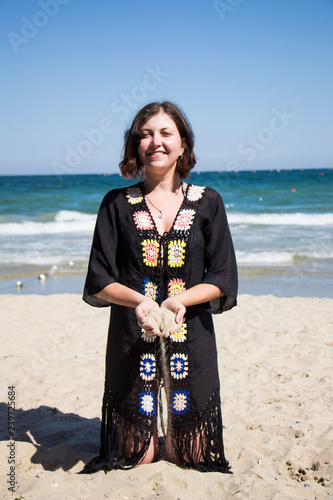 Sand falling from the woman's hand. Beautiful young woman on the beach with sand in her hand. photo